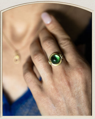 Hand modeling green tourmaline cabochon ring set in gold. 