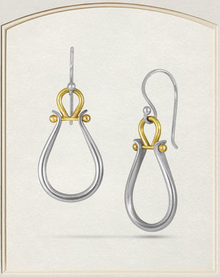 A pair of silver and gold drop earrings with a teardrop-shaped silver dangle and an ornate gold top detail, shown on a light cream textured background with a subtle arched border.
