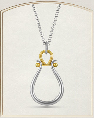 A two-tone metal pendant featuring a silver teardrop-shaped loop with a gold top loop and small gold accent beads hanging on a chain, displayed on a textured cream background.