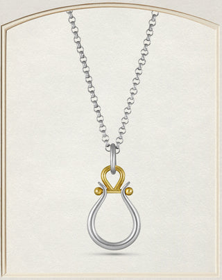 A two-tone metal pendant on a chain featuring a silver teardrop loop and a gold heart-shaped top with small gold beads, centered on a textured cream background with a decorative border.